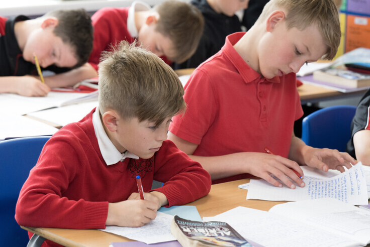 Children writing in exercise books.