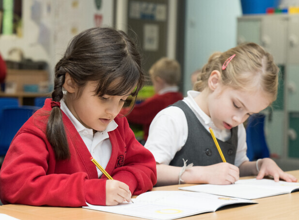Two children writing in exercise books.