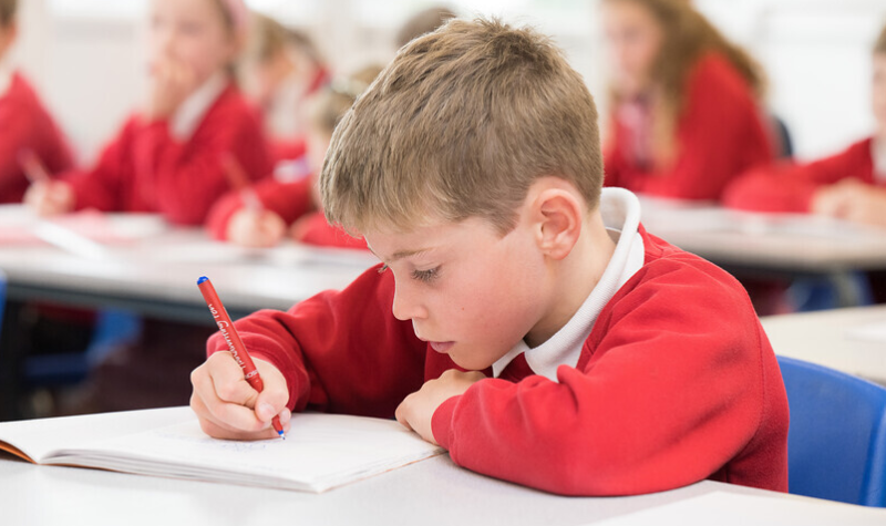 Child writing in exercise book.