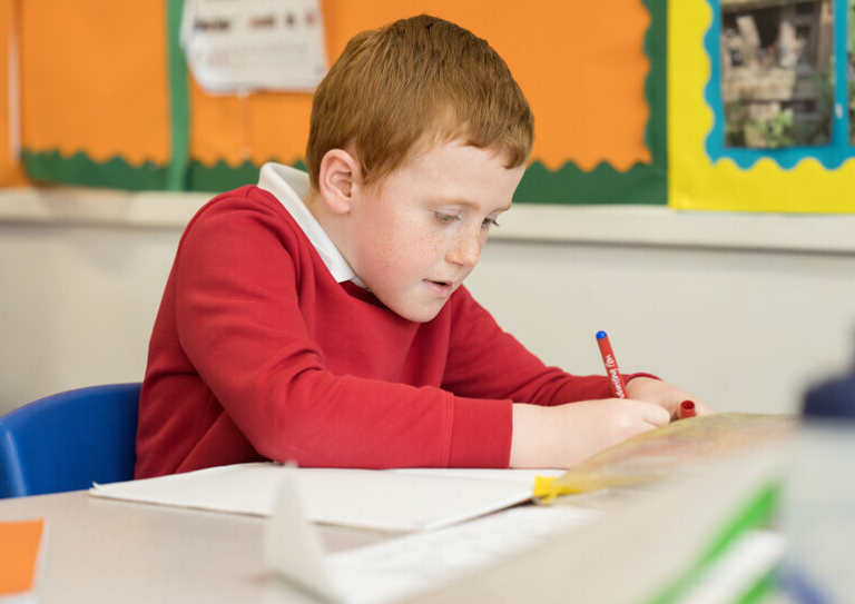 Child writing in exercise book.