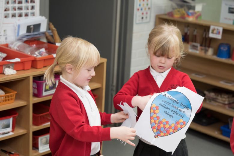 Children cutting out a picture of a balloon and talking.