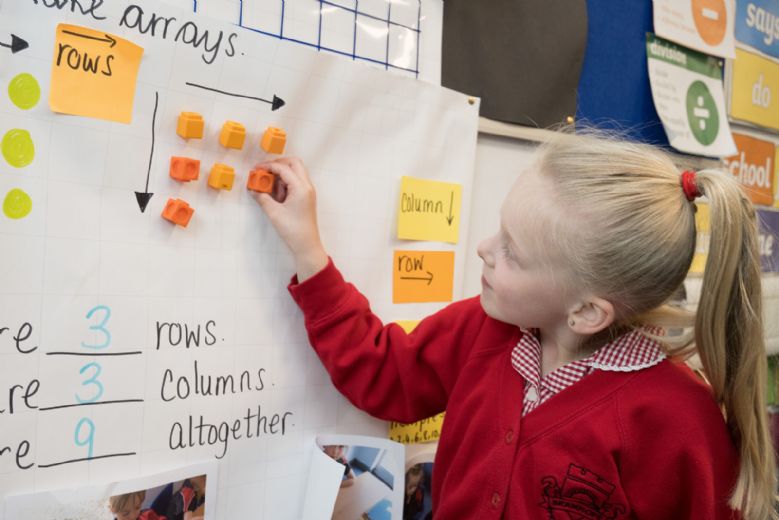 Child kneeling working with number array display.
