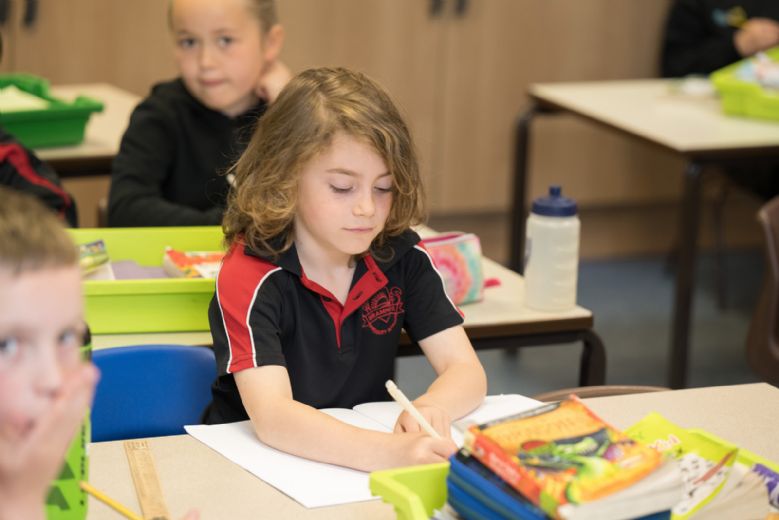 Child writing in exercise book.