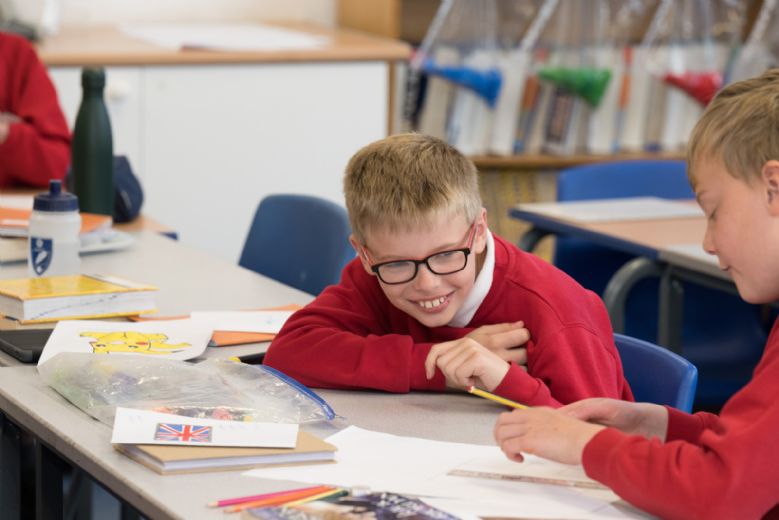 Child laughing while working with friend at desk.