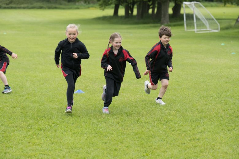 Children racing towards the camera on the school field.