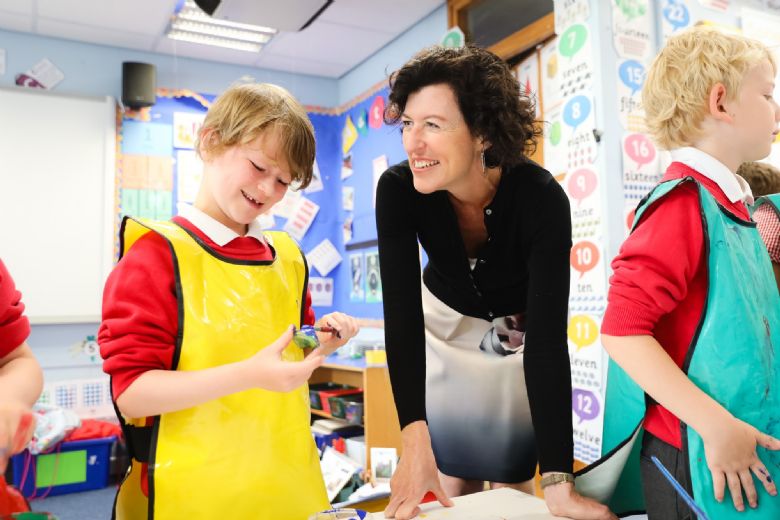 Rachel Colbourn smiling with  young child in yellow plastic apron.