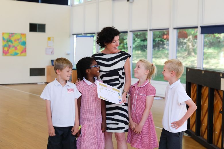 Rachel Colbourn in the middle of four children, all smiling and chatting.