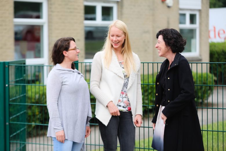 Two parents talking and laughing with Rachel Colbourn.